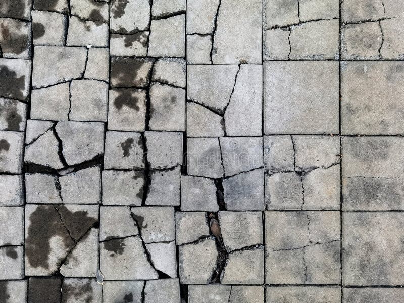 Top view texture of the brick blocks floor in the cracks. The surface of the public outdoor walkway or pavement is broken and stock photography