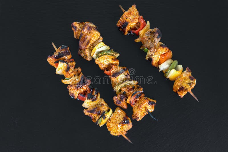 Top view from three grilled shaslik skewers served on a slate wi