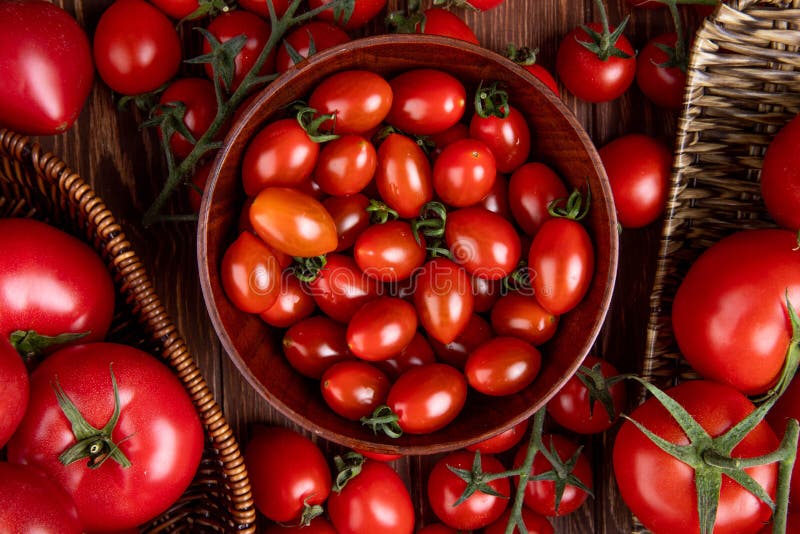 top view of tomatoes in bowl basket and plate on wooden background