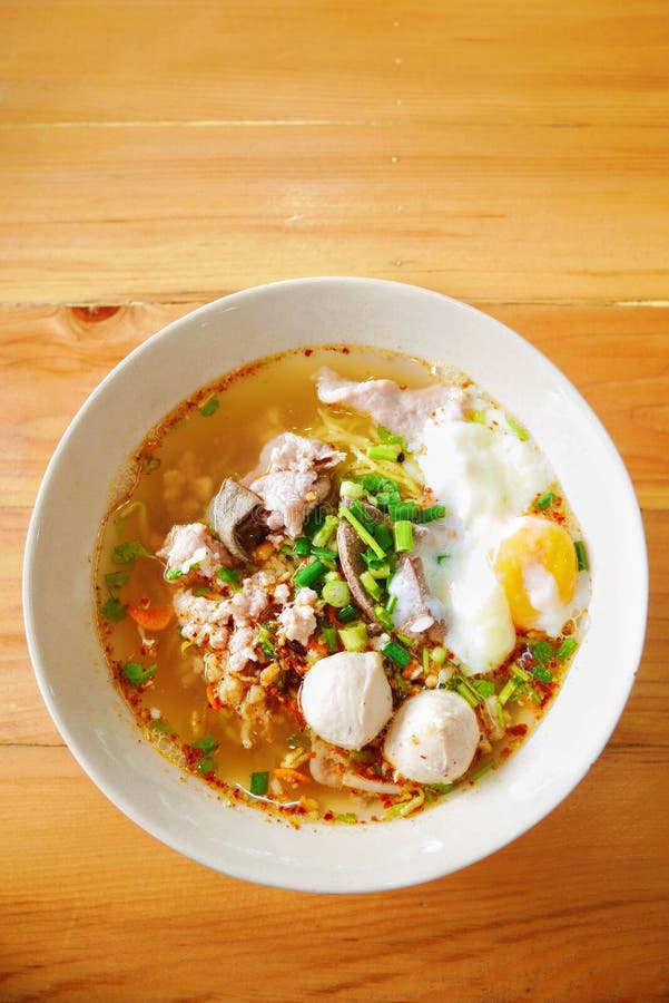 Tomyum Egg noodle with minced pork, meatballs and egg in a bowl on the table wood. Tomyum is a very popular food recipe in Thailand. Tomyum Egg noodle with minced pork, meatballs and egg in a bowl on the table wood. Tomyum is a very popular food recipe in Thailand.