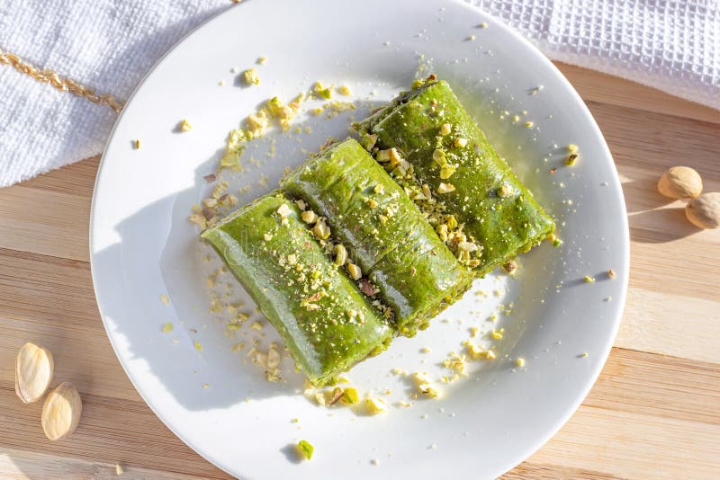 Top view of traditional East Asian sweet baked pistachio bahlava or pahlava with nuts and syrup on a white plate royalty free stock photo Top view of traditional East Asian sweet baked pistachio bahlava or pahlava with nuts and syrup on a white plate royalty free stock photo