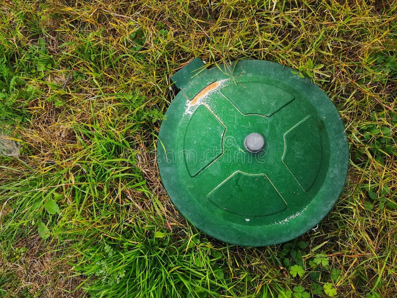 Top View of an Underground Gas Tank Cap in a Meadow Under the Sunlight