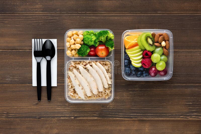 Wholesome nutrient rich food set in take away boxes with spoon and fork on wood table ready to eat