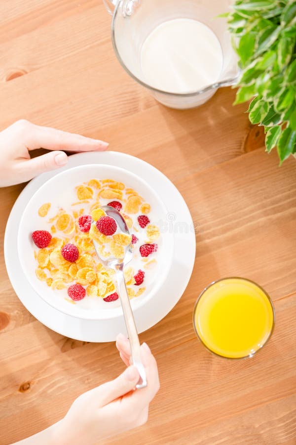 Top view of woman eating cereals with strawberry and milk