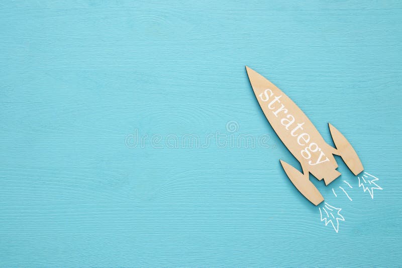 Top view of wooden rocket with word - strategy - over blue background. royalty free stock photography