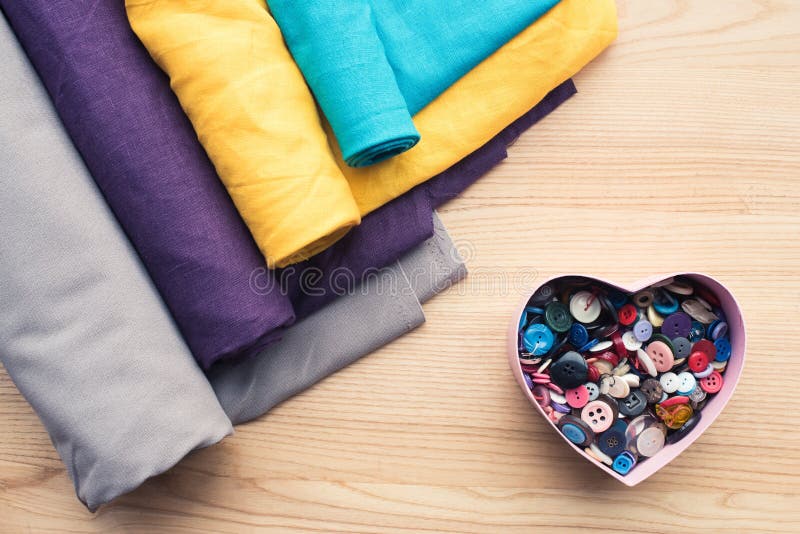 top view of wooden table with rolls of fabric and heart shaped box