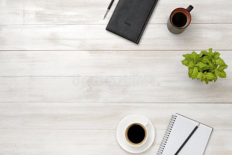 Top view workplace with cup of coffee, pot plant, notebook, pencil and pen on wooden table