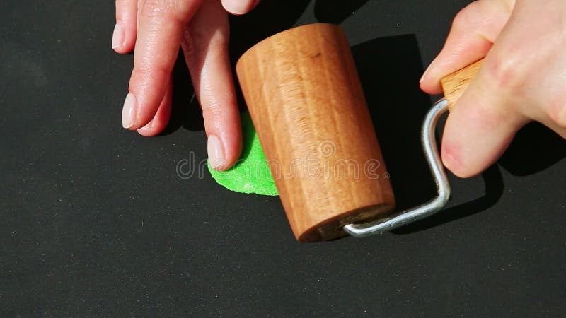 Topaanzicht de handen van de vrouw met een houten rolstukje groene marsepeinmassa