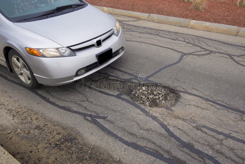 Pot hole or pothole image of a broken cracked asphalt pavement as a transportation symbol of road maintenance and the car insurance risk to auto suspensions. Pot hole or pothole image of a broken cracked asphalt pavement as a transportation symbol of road maintenance and the car insurance risk to auto suspensions.