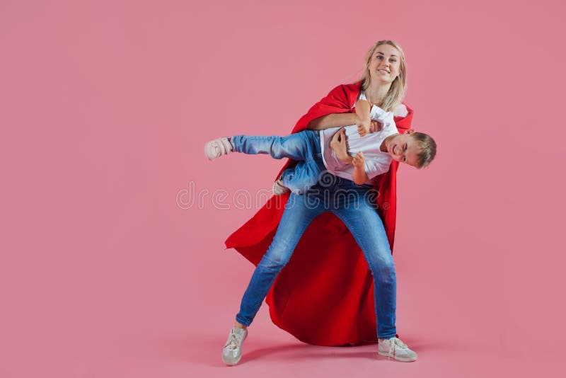 Toppen mamma den lyckliga familjen, en ung blond kvinna i en röd udde och hennes son hoppar och tar av arkivfoto Toppen mamma den lyckliga familjen, en ung blond kvinna i en röd udde och hennes son hoppar och tar av arkivfoto