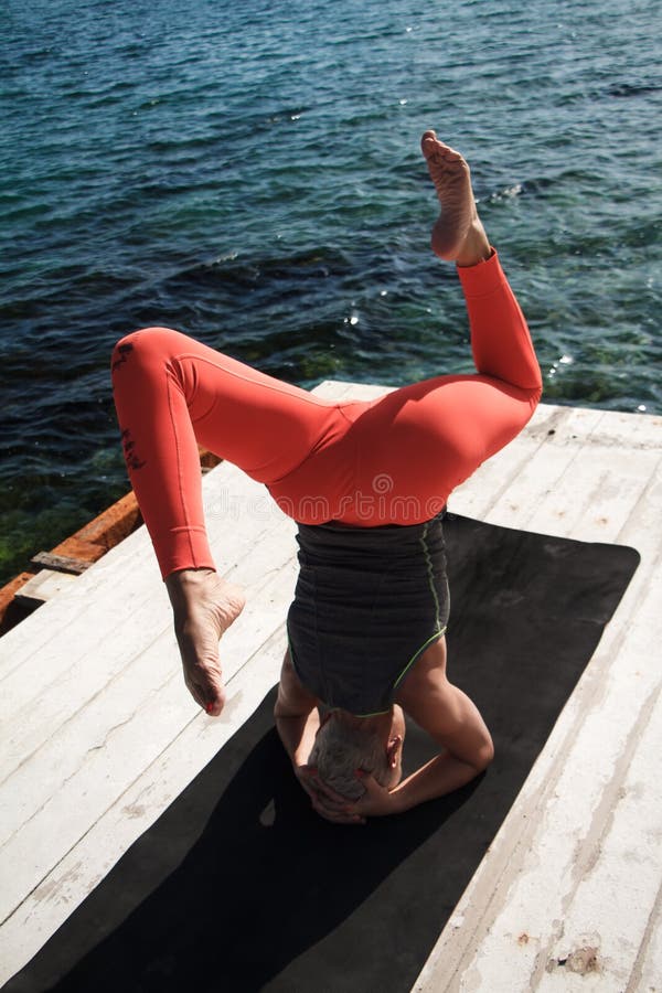 Topview-Portrait von erwachsenen blond-Frau mit kurzen Haarschnitt-Praktiken Yoga auf der Pier vor dem Hintergrund des Meeres und stockbilder Topview-Portrait von erwachsenen blond-Frau mit kurzen Haarschnitt-Praktiken Yoga auf der Pier vor dem Hintergrund des Meeres und stockbilder