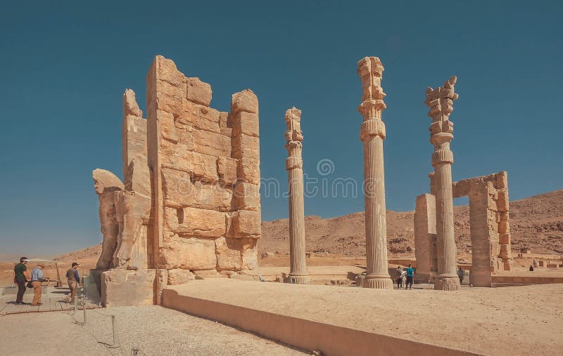 Tore mit Spalten und eindrucksvollen Ruinen zu verlassener Stadt und Touristen, die hinter Monumente gehen persepolis lizenzfreie stockfotos Tore mit Spalten und eindrucksvollen Ruinen zu verlassener Stadt und Touristen, die hinter Monumente gehen persepolis lizenzfreie stockfotos
