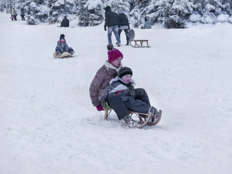Torfhaus Alemanha 3 JANUAR 2015: A mãe e o filho estão indo abaixo de um monte na neve Feriados de escola do inverno foto de stock Torfhaus Alemanha 3 JANUAR 2015: A mãe e o filho estão indo abaixo de um monte na neve Feriados de escola do inverno foto de stock