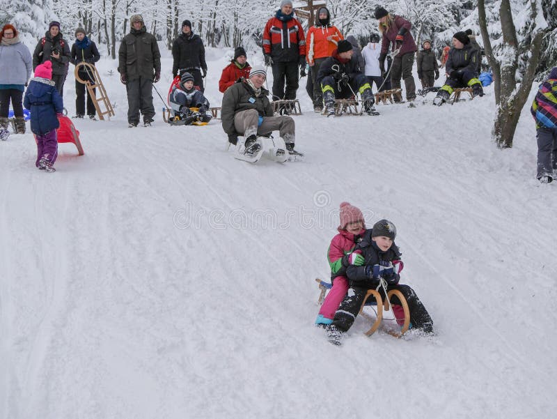 Torfhaus, Alemania - 3 JANUAR 2015: Niños que van abajo de una colina en la nieve Resto activo de los deportes de la familia en i foto de archivo Torfhaus, Alemania - 3 JANUAR 2015: Niños que van abajo de una colina en la nieve Resto activo de los deportes de la familia en i foto de archivo