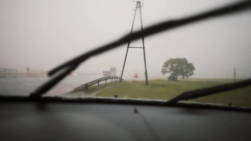 Torkare som arbetar i regnet på en vindruta Sikt av en väg med bilar