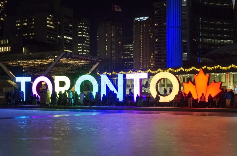 TORONTO, CANADA - 2018-01-01: La gente davanti a TORONTO firma con l'albero di Natale nella notte osservata attraverso pattinare fotografia stock libera da diritti TORONTO, CANADA - 2018-01-01: La gente davanti a TORONTO firma con l'albero di Natale nella notte osservata attraverso pattinare fotografia stock libera da diritti