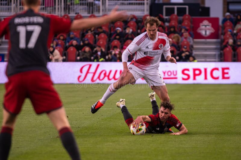 Toronto, ON, Canada - April 20, 2024: Henry Kessler #4 defender of the New England Revolution jumps over the opponent during the MLS Regular Season match between Toronto FC (Canada) and New England Revolution (USA) at BMO Field. Toronto, ON, Canada - April 20, 2024: Henry Kessler #4 defender of the New England Revolution jumps over the opponent during the MLS Regular Season match between Toronto FC (Canada) and New England Revolution (USA) at BMO Field