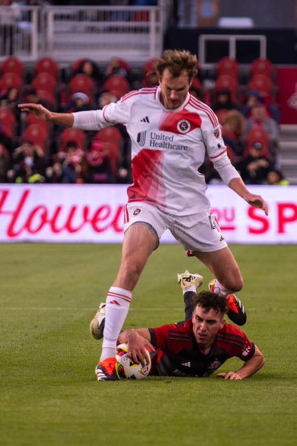 Toronto, ON, Canada - April 20, 2024: Henry Kessler #4 defender of the New England Revolution jumps over the opponent during the MLS Regular Season match between Toronto FC (Canada) and New England Revolution (USA) at BMO Field. Toronto, ON, Canada - April 20, 2024: Henry Kessler #4 defender of the New England Revolution jumps over the opponent during the MLS Regular Season match between Toronto FC (Canada) and New England Revolution (USA) at BMO Field