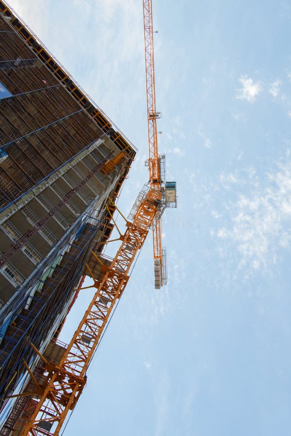 Torre amarilla de la grúa de construcción y edificio incompleto con el cielo azul imagen de archivo libre de regalías Torre amarilla de la grúa de construcción y edificio incompleto con el cielo azul imagen de archivo libre de regalías