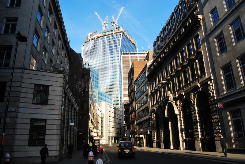 The Walkie Talkie tower at 20 Fenchurch Street under construction, seen from Fenchurch Street by Mark Lane, blue sky, and tower cranes. The Walkie Talkie tower at 20 Fenchurch Street under construction, seen from Fenchurch Street by Mark Lane, blue sky, and tower cranes.