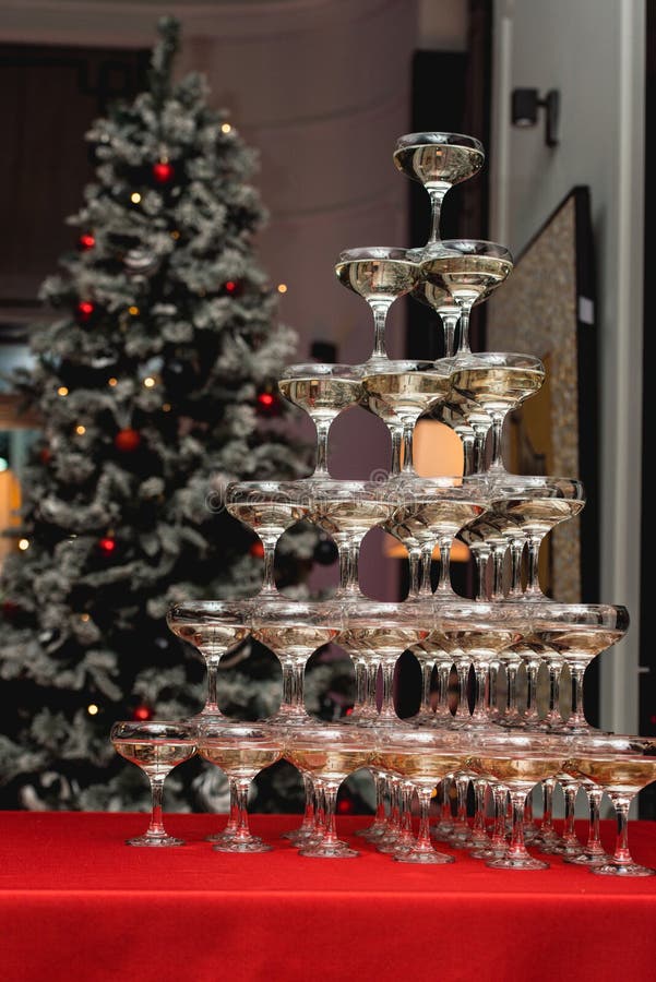 Torre di Champagne su una tavola rossa con l'albero di Natale nei precedenti fotografie stock Torre di Champagne su una tavola rossa con l'albero di Natale nei precedenti fotografie stock