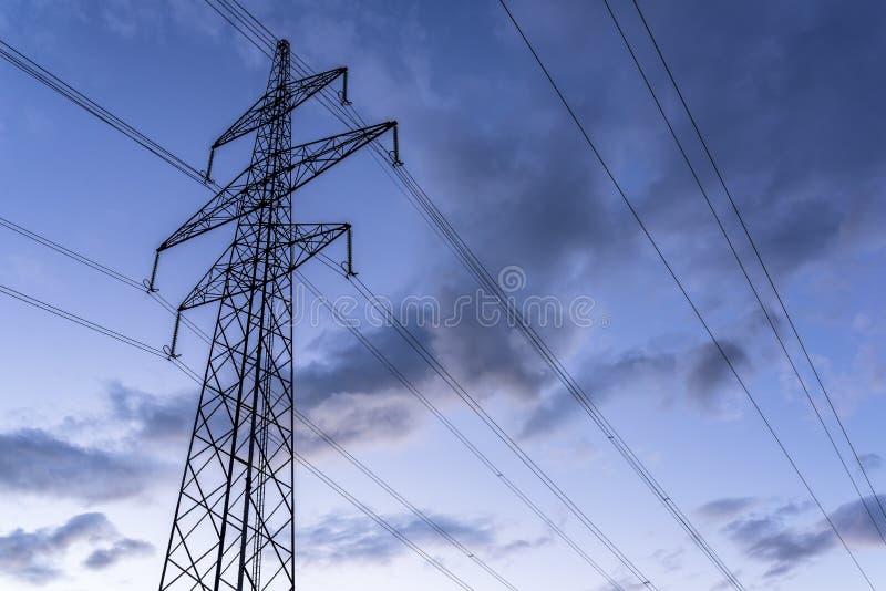 Electric tower and wires against cloudy sky at dusk. Electric tower and wires against cloudy sky at dusk.