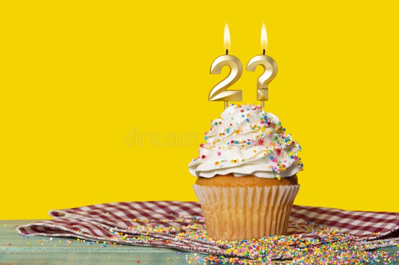 Birthday Cupcake With Candle Number 2 And Question Mark - Photo On Yellow Background. Birthday Cupcake With Candle Number 2 And Question Mark - Photo On Yellow Background.