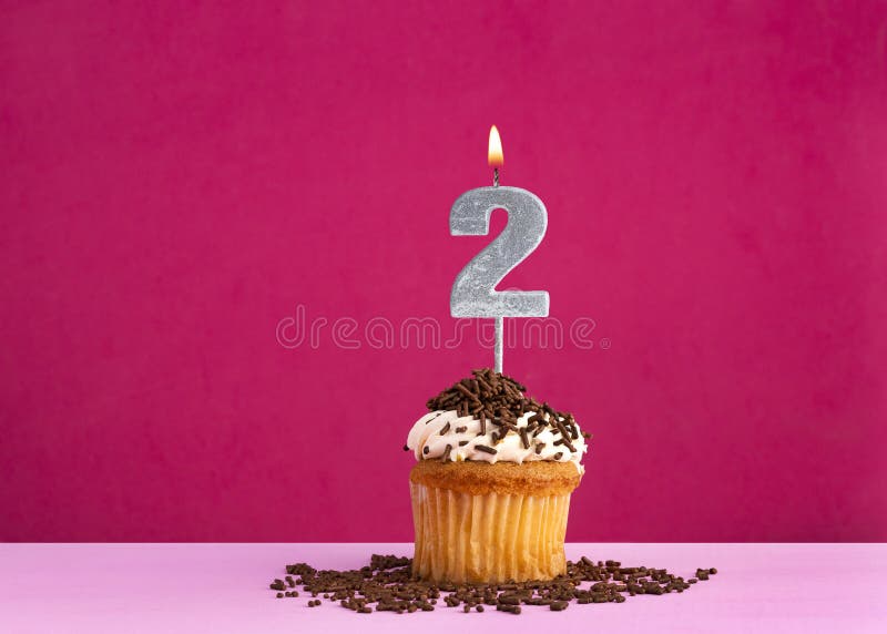 Birthday celebration with candle number 2 - Chocolate cupcake on pink background. Birthday celebration with candle number 2 - Chocolate cupcake on pink background