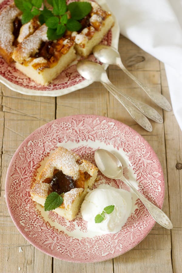 Torta con le prugne e le pesche, servite con una palla del gelato alla vaniglia e le foglie della melissa immagini stock Torta con le prugne e le pesche, servite con una palla del gelato alla vaniglia e le foglie della melissa immagini stock