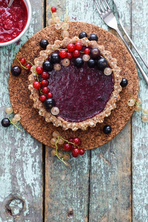 Torta crua do vegetariano com doce da baga e os corintos orgânicos no backgr azul fotos de stock royalty free Torta crua do vegetariano com doce da baga e os corintos orgânicos no backgr azul fotos de stock royalty free