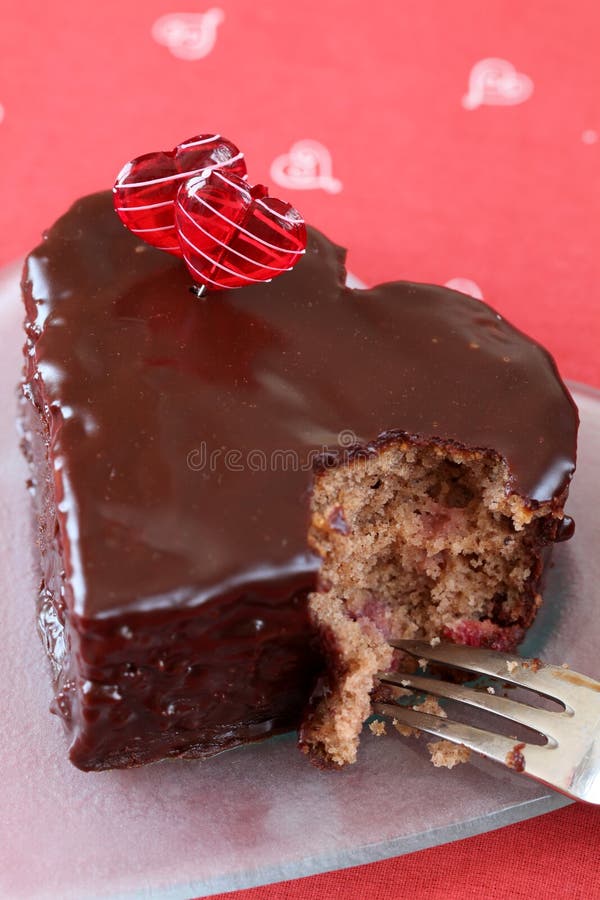 Torta di cioccolato a forma di del cuore con un morso fotografia stock Torta di cioccolato a forma di del cuore con un morso fotografia stock