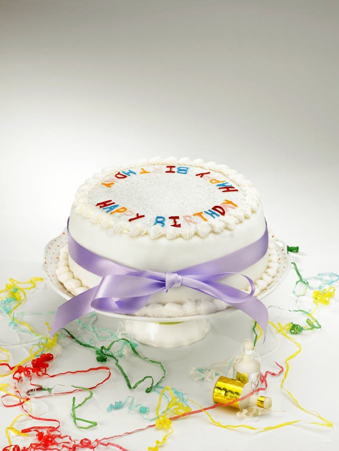 A white birthday cake on cakestand with party streamers. A white birthday cake on cakestand with party streamers