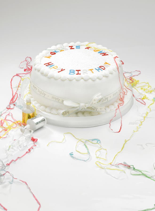 A white birthday cake with streamers on a white surface. A white birthday cake with streamers on a white surface.