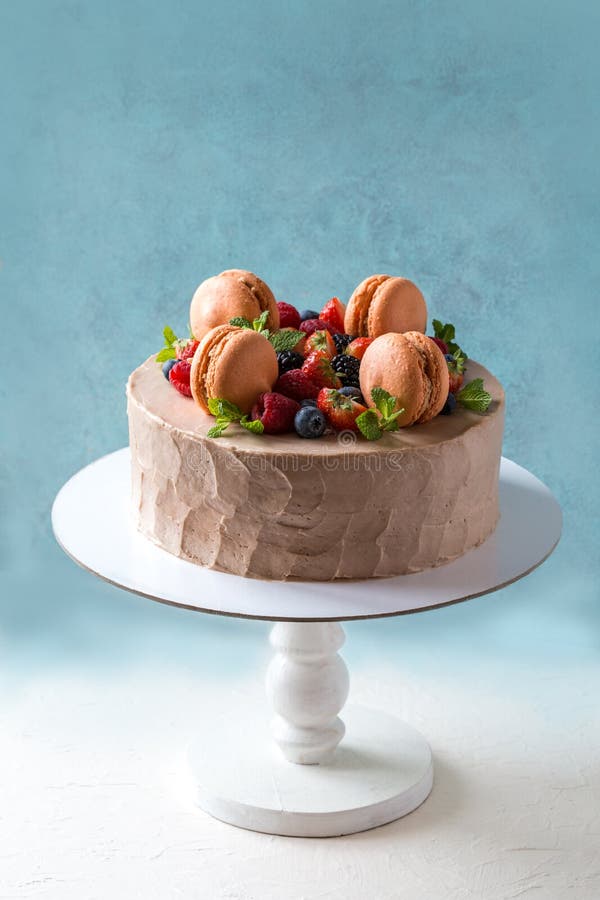 Torta hecha en casa con el macaron y fruta fresca, bayas en fondo azul imagen de archivo Torta hecha en casa con el macaron y fruta fresca, bayas en fondo azul imagen de archivo