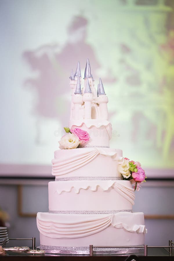 Torta nunziale decorata con i fiori e un castello immagini stock Torta nunziale decorata con i fiori e un castello immagini stock