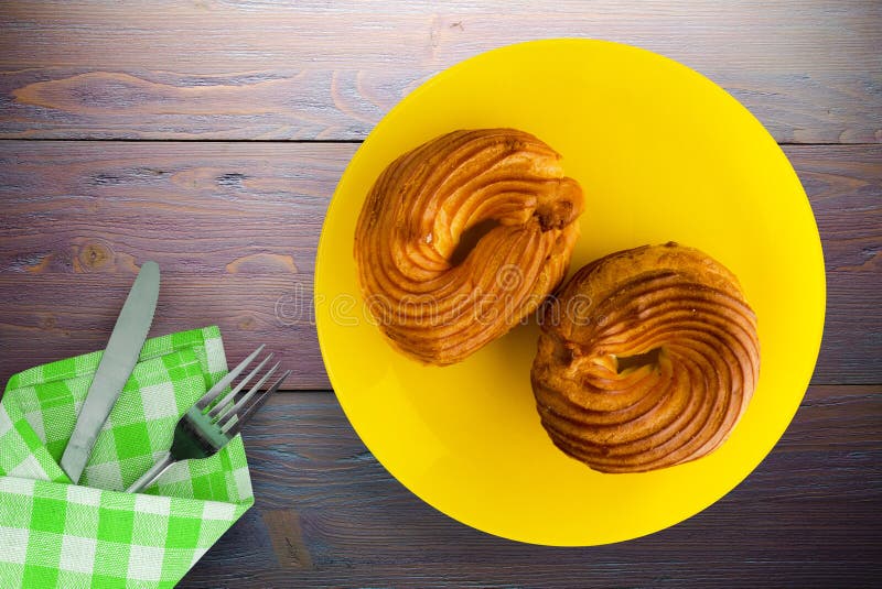 Torta in scatola su un piatto. Torta in crema di latte su un piatto giallo con forchetta, coltello e frutta. dolce in legno di colore viola. vista dall'alto