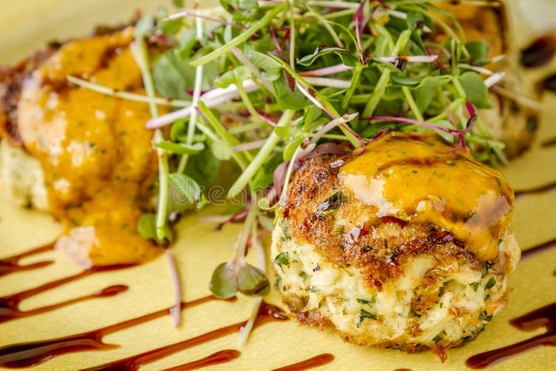 Pan seared blue crab cakes topped with roasted tomato basil aioli and micro green with balsamic glaze. Pan seared blue crab cakes topped with roasted tomato basil aioli and micro green with balsamic glaze