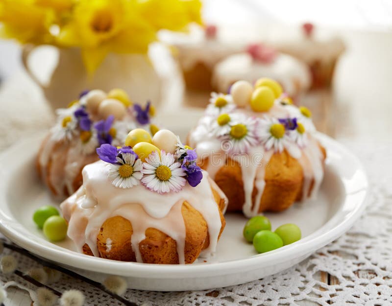 Easter cakes covered with icing decorated with spring and edible flowers and marzipan eggs on an Easter table. Easter delicious dessert. Easter cakes covered with icing decorated with spring and edible flowers and marzipan eggs on an Easter table. Easter delicious dessert