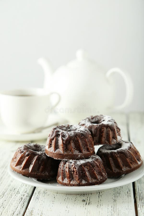 Chocolate bundt cakes on plate on white wooden background. Chocolate bundt cakes on plate on white wooden background