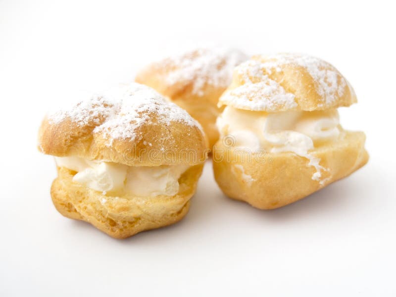 Cream puffs and eclairs cakes with filling, powdered sugar topping. Cream puffs and eclairs cakes with filling, powdered sugar topping