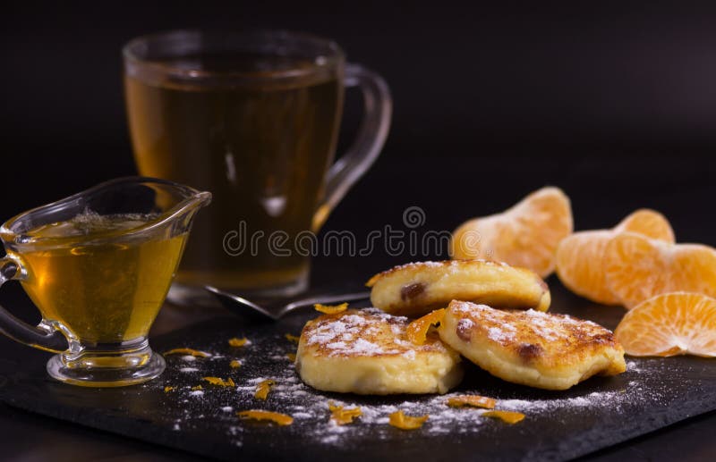 Torte di formaggio con l'uva passa, le patatine fritte del mandarino e lo zucchero in polvere Dopo saranno le fette di mandarino, immagini stock Torte di formaggio con l'uva passa, le patatine fritte del mandarino e lo zucchero in polvere Dopo saranno le fette di mandarino, immagini stock