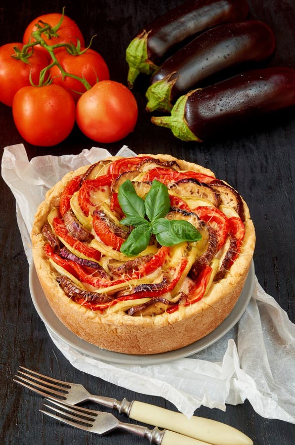 Torte mit Auberginen, Tomaten und Käse auf der grauen Platte verziert mit frischen Basilikumblättern und Weinlesegabeln Selbst ge stockfotografie Torte mit Auberginen, Tomaten und Käse auf der grauen Platte verziert mit frischen Basilikumblättern und Weinlesegabeln Selbst ge stockfotografie
