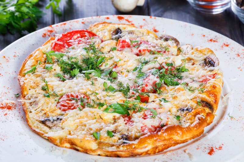 Tortilla con las rebanadas jamón, setas, verdes, queso y tomate en fondo de madera oscuro imagenes de archivo Tortilla con las rebanadas jamón, setas, verdes, queso y tomate en fondo de madera oscuro imagenes de archivo