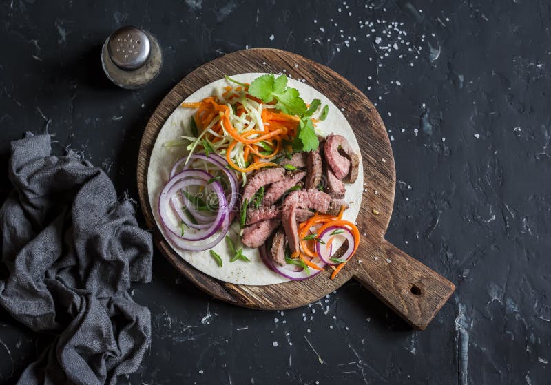 Tortilla mit Rindfleischsteak, marinierten Karotten und Kohl Köstlicher Mittagessensnack Auf einem dunklen Hintergrund stockbilder Tortilla mit Rindfleischsteak, marinierten Karotten und Kohl Köstlicher Mittagessensnack Auf einem dunklen Hintergrund stockbilder