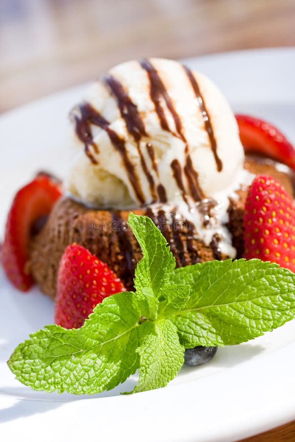 Chocolate volcano Lava cake A la Mode with strawberries, mint leaf and vanilla ice cream topped with chocolate syrup. Chocolate volcano Lava cake A la Mode with strawberries, mint leaf and vanilla ice cream topped with chocolate syrup