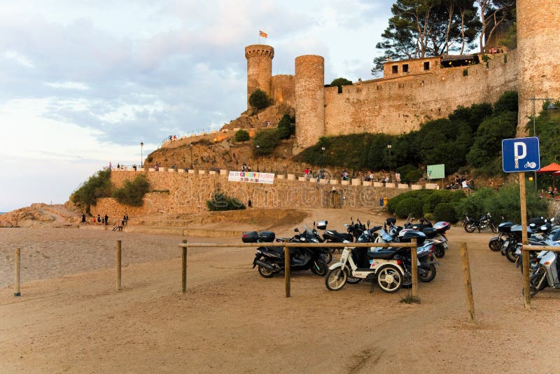 Tossa de Mar, Catalogna, Spagna, agosto 2018 Vista della fortezza e parcheggio dei motocicli al tramonto fotografia stock Tossa de Mar, Catalogna, Spagna, agosto 2018 Vista della fortezza e parcheggio dei motocicli al tramonto fotografia stock