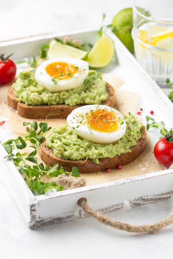 Tostada con pur? del aguacate y el huevo pasado por agua en la bandeja blanca, yema de huevo l?quida, desayuno delicioso, bocadil fotos de archivo libres de regalías Tostada con pur? del aguacate y el huevo pasado por agua en la bandeja blanca, yema de huevo l?quida, desayuno delicioso, bocadil fotos de archivo libres de regalías