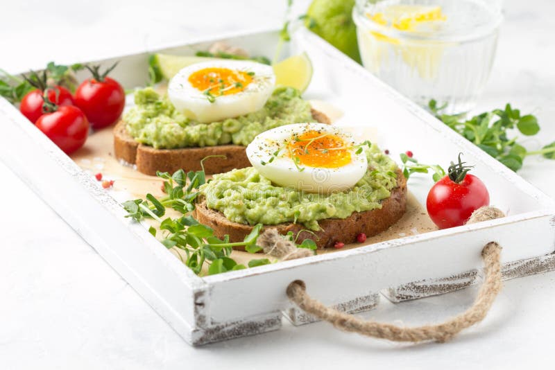 Tostada con pur? del aguacate y el huevo pasado por agua en la bandeja blanca, yema de huevo l?quida, desayuno delicioso, bocadil fotos de archivo libres de regalías Tostada con pur? del aguacate y el huevo pasado por agua en la bandeja blanca, yema de huevo l?quida, desayuno delicioso, bocadil fotos de archivo libres de regalías