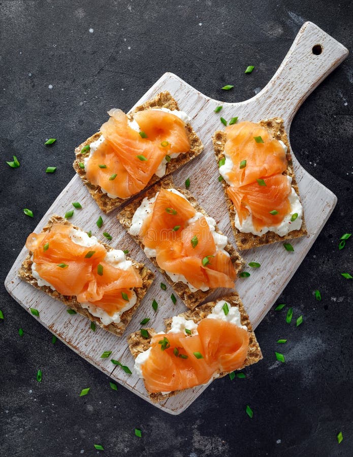 Tostada hecha en casa del biscote curruscante con el salmón ahumado y chees suaves, cebolletas en el tablero blanco imágenes de archivo libres de regalías Tostada hecha en casa del biscote curruscante con el salmón ahumado y chees suaves, cebolletas en el tablero blanco imágenes de archivo libres de regalías