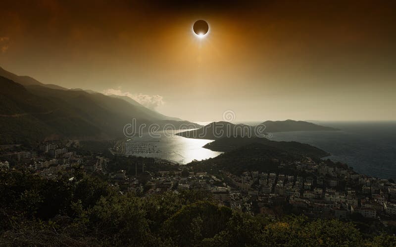 Total solar eclipse in dark red glowing sky above seaside city